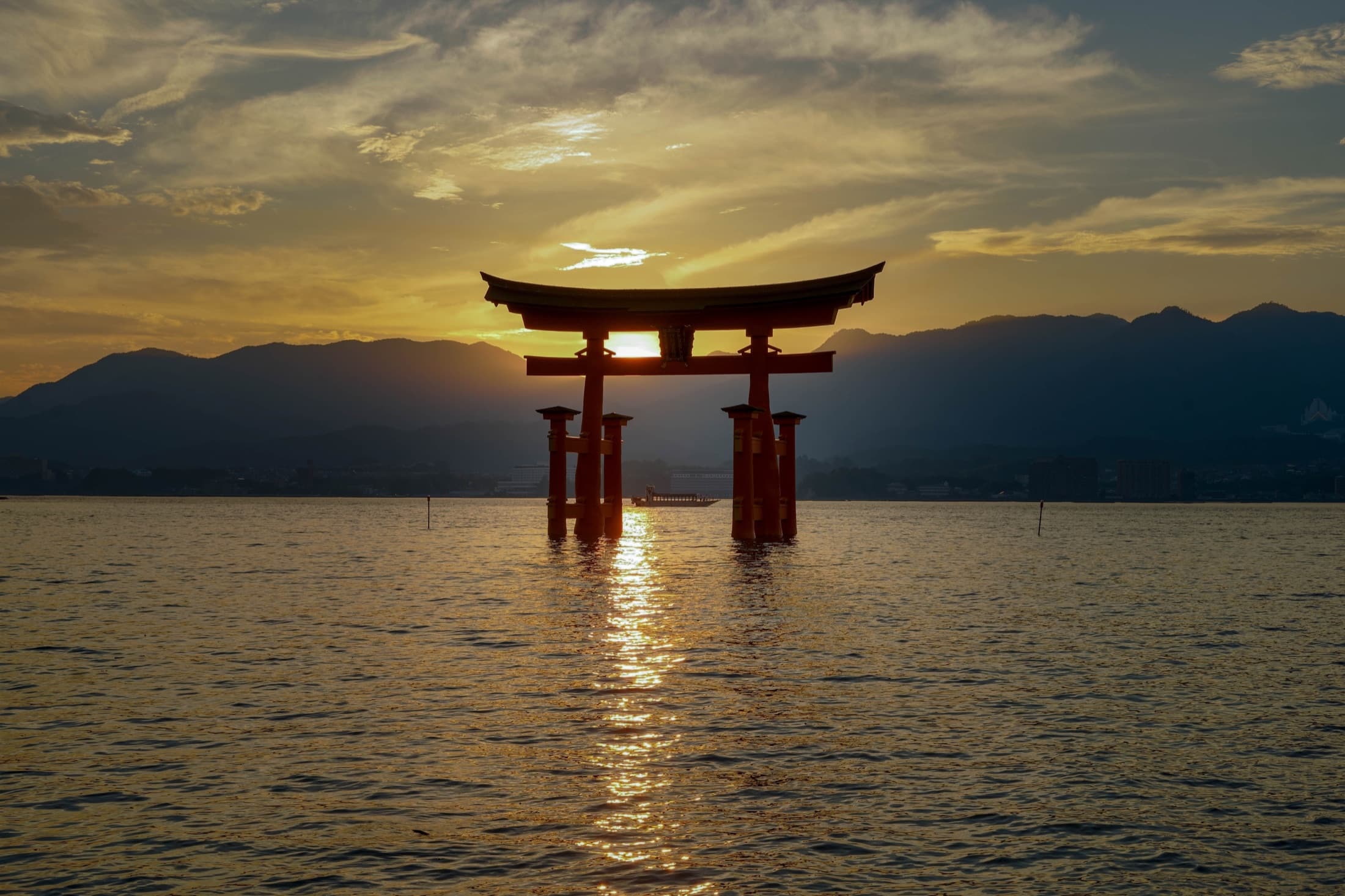 Floating torii gate of Itsukushima Shrine backlit at sunset.