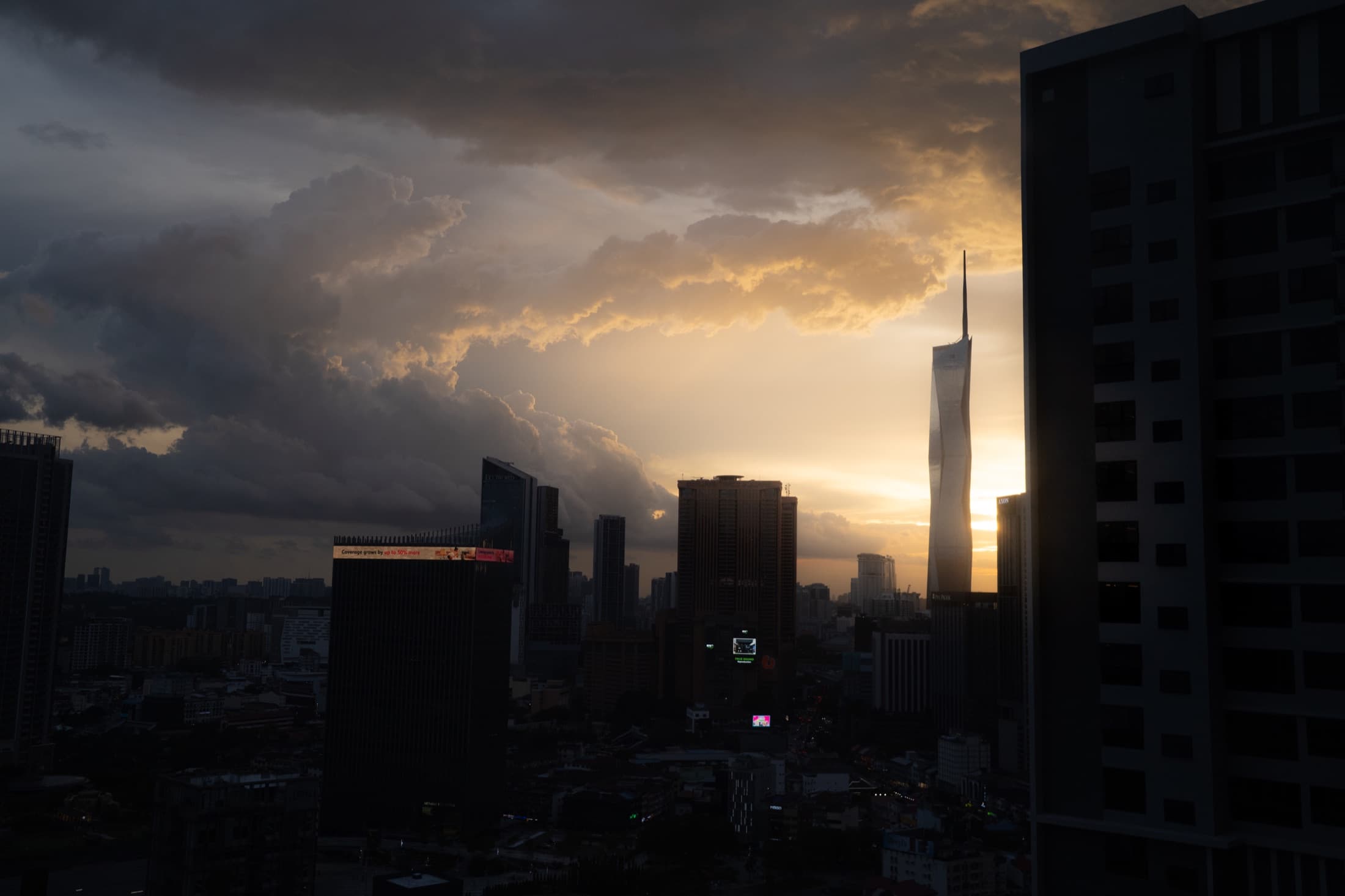 Storm clouds breaking over the Kuala Lumpur skyline at sunset.