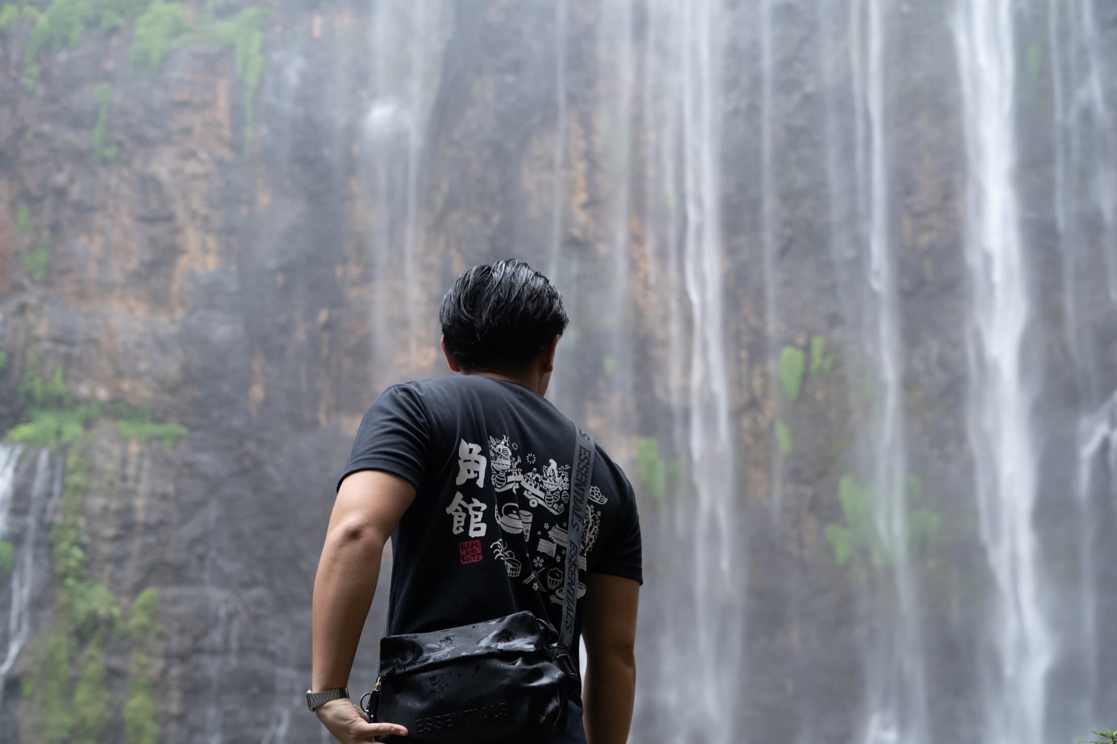 A figure looking up at Tumpak Sewu waterfall in eastern Java.